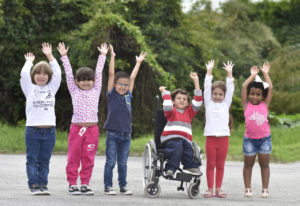 Foto de crianças em pé, com os braços levantados