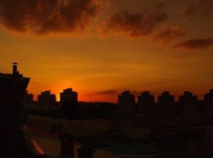 Foto de amanhecer com céu alaranjado e perfis de edifícios