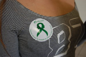 Foto de adesivo de campanha contra o câncer colado em blusa de mulher