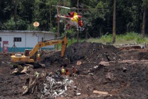 Foto de trator e helicóptero removendo lodo de rejeitos de minério de ferro