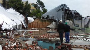 Homens olham casas e galpões destruídos pelos fortes ventos em Santa Catarina